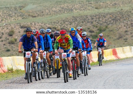 Mountain bikers group racing on road in desert