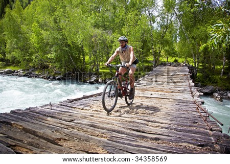 Mountain biker goes on old wooden bridge