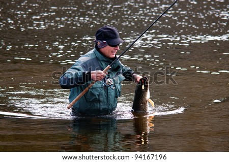 Fisherman with pike fish on the shore of river Uur in northern Mongolia