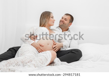 Pregnant lying on the bed with her husband