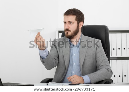happy man businessman at his desk lets a paper airplane
