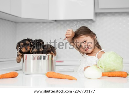 little girl playing with a puppy dog in the kitchen