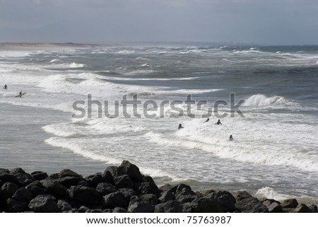 Surfers wading into the sea in stormy weather