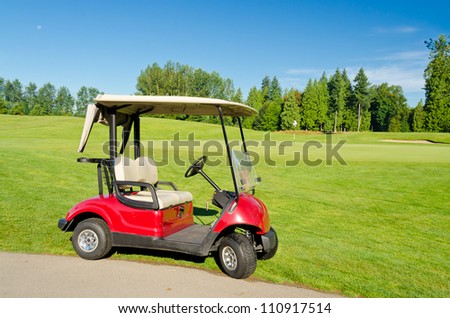 Red golf cart over nice green and blue sky