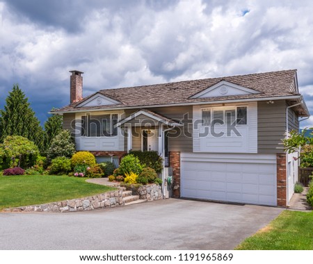 A perfect neighborhood. Houses in suburb at Summer in the north America. Fragment of a luxury house with nice window over dramatic cloudy sky.