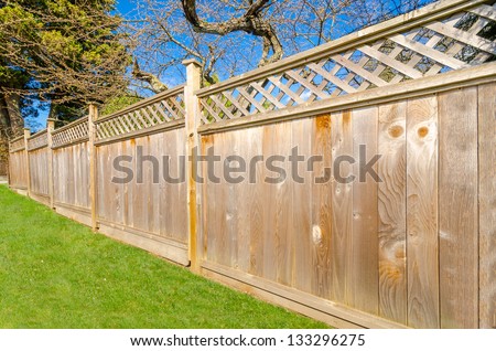 wooden fence with green lawn and trees