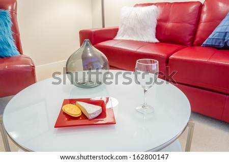 Interior design with couch, colorful cushions, glass and cheese with crackers on end table