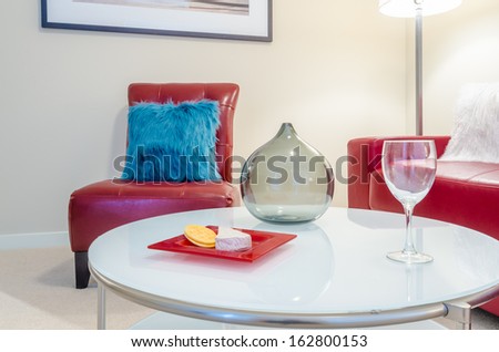 Interior design with couch, colorful cushions, glass and cheese with crackers on end table