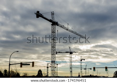 Construction site with cranes at sunset, sunrise, dawn time with the cranes as a silhouette. Vancouver, Canada. Horizontal.