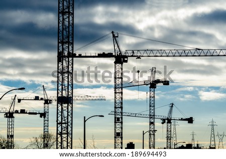 Construction site with cranes at sunset, sunrise, dawn time with the cranes as a silhouette. Vancouver, Canada. Horizontal.