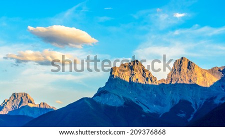 Scenery of high mountain peak at sunset (sunrise) and blue sky with white clouds. Contrast shadow.