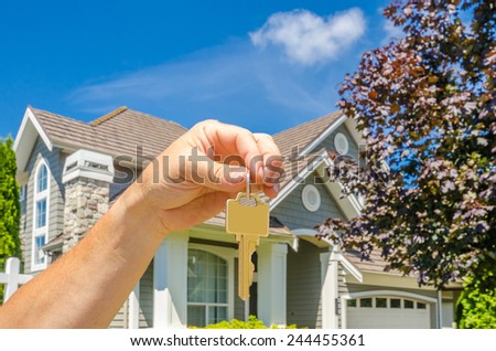 Hand holding the keys for a big custom made luxury house for sale, house of dream in the suburbs of Vancouver, Canada. Horizontal.