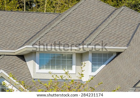 The roof of the house with nice window and white frame.