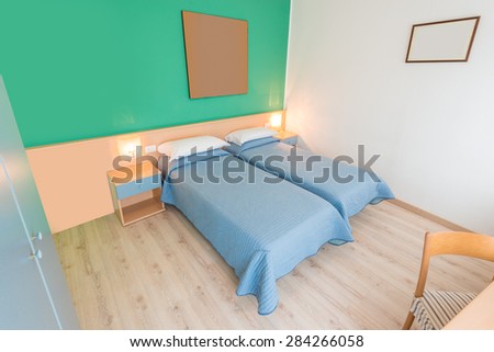 Beautiful and modern home and hotel bedroom interior design. Green walls, blue blankets and hardwood floor.