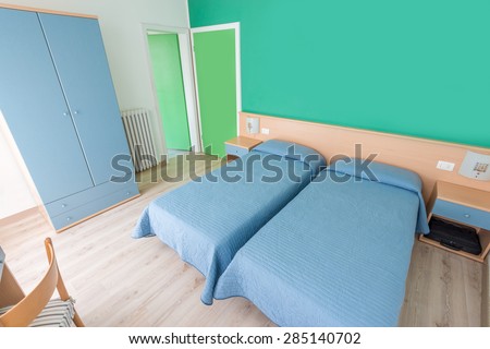 Beautiful and modern home and hotel bedroom interior design. Green walls, blue blankets and hardwood floor.