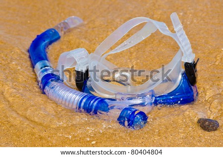 Diving mask and snorkel on gold sand.