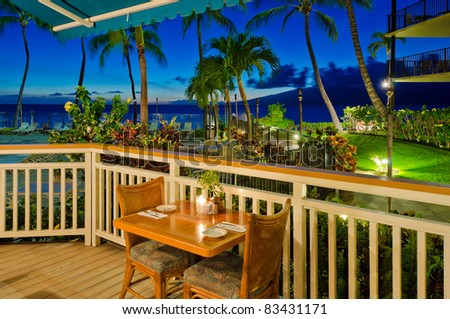 Fragment of an indoor and outdoor restaurant in night illumination over pool and ocean view