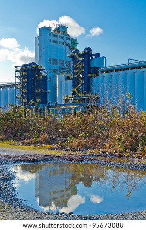 Industrial building and its reflection in the puddle on the gravel road