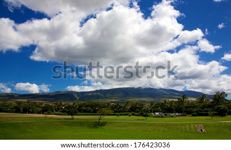 Green Hawaiian landscape set against a blue sky with large white clouds