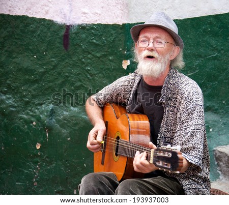 BOGOTA, COLOMBIA - MAY 06, 2014: An unidentified old musician playing for money in the streets of La Candelaria the historic center of Bogota. Colombia\'s capital city was founded here in 1538