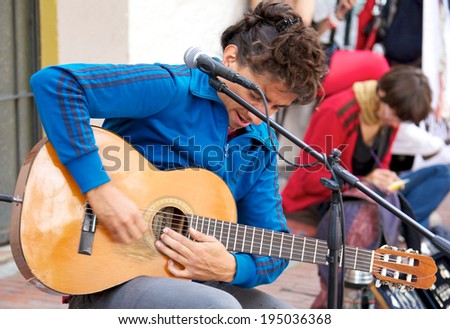 BOGOTA, COLOMBIA - APRIL 06, 2014: An unidentified musician playing guitar for money in the streets of Usaquen in Bogota Colombia. Usaquen was declared a national monument in 1987.