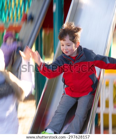 Little boy sliding down a slide at the park with motion blur