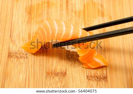 Picking up a piece of salmon sushi with chop sticks