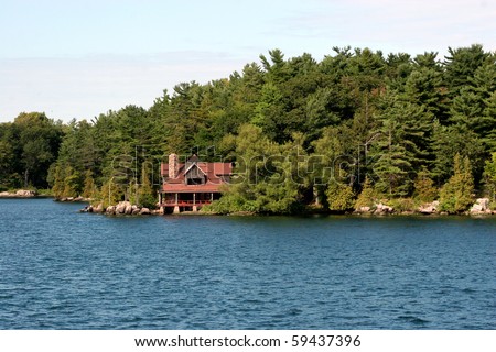 A large cabin surrounded by a forest on a large blue lake