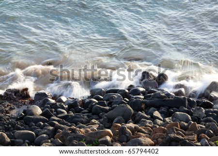 Gentle waves crashing against the rocky shore in Kihei Maui