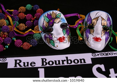 Two Mardi Gras masks and beads with Bourbon Street sign.