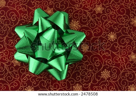 Green bow on a red and gold holiday background. Text space on right side of image.