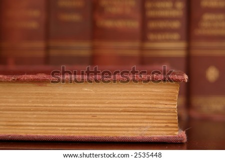 Closeup image of the old worn pages of a book from the front edge with out of focus books standing in the background.