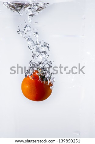 red tomato splashing into water