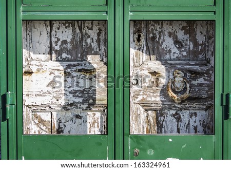 Antique massive wooden door behind a metal door
