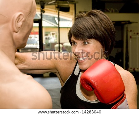 Attractive mature woman practicing boxing with a dummy.