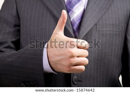 Business man in suit offers a thumbs-up gesture indicating  approval, agreement, etc.