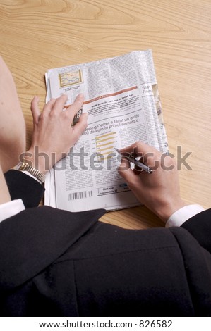 somebody is reading the newspaper, with a pen in hand