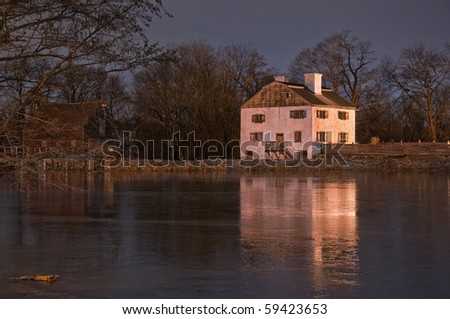 A long exposure on a frozen night in Sleepy Hollow, New York of the 18th century Philipsburg Manor reflecting off the frozen pond.