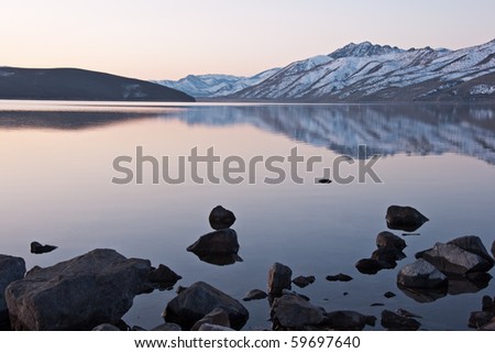 The sunrise reflects on the lake and the surrounding snow covered mountains in Topaz lake, Nevada.