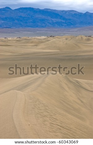 The layers of sky, mountain, desert, and sand dune as seen from the middle of Mesquite Flat Sand Dunes in Death Valley National Park, California.