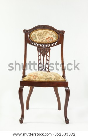 Front view of an antique Art Nouveau mahogany parlour chair with curved flowing lines and carved fruit and flower detail typical of the era over a white background