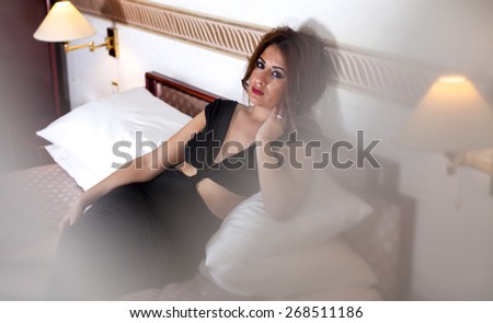 Sexy and beautiful young girl in bed waiting for her lover. Sad thinking tormented stressed and worried woman with problems. Indoor shot.