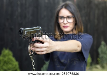 Close up Young Woman in T-Shirt Holding a Hand Gun with her Both Hands