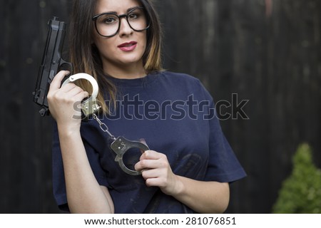 Close up Sexy Girl in T-Shirt Holding a Hand Gun and a pair of handcuffs