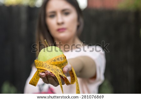 Healthy happy woman with apple and tape measure for diet