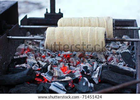 chimney cake baking on a spit over charcoal fire