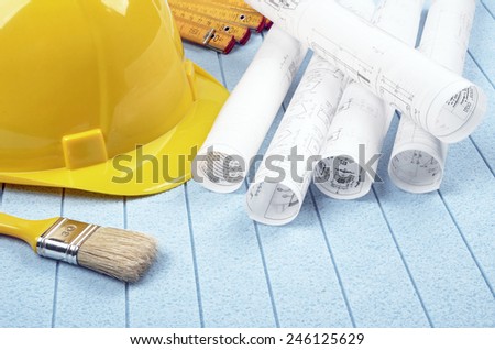 Yellow helmet,meter and brush, home improvement plans on background  styrofoam
