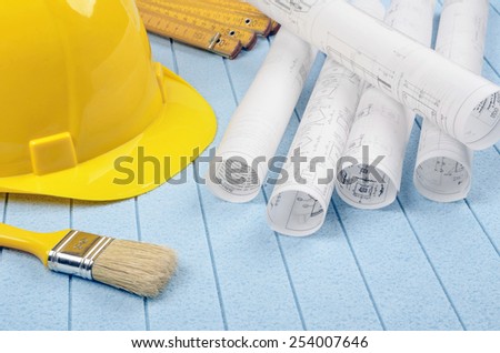 Yellow helmet,meter and brush, home improvement plans on background styrofoam
