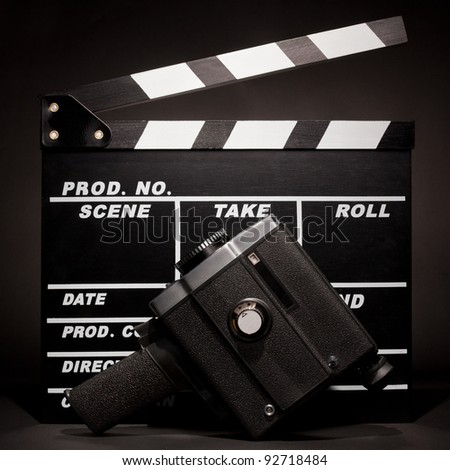 Film slate and an old movie camera on dark background.