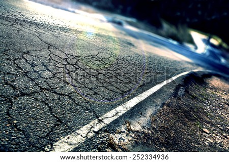 Travel concept. Cracked asphalt and curve road.Road lines